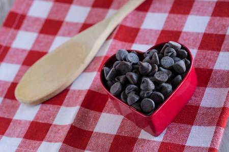 Valentines Day baking chocolate chips in cookie cutter with wood spoonの写真素材