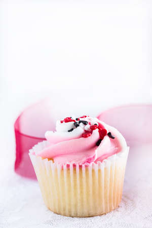 Single Valentines Day cupcake with heart sprinkles and red ribbonの写真素材