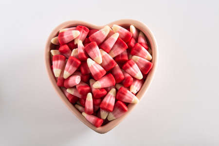 Valentines Day candy corn sweets in heart shaped bowl on white background horizontalの写真素材