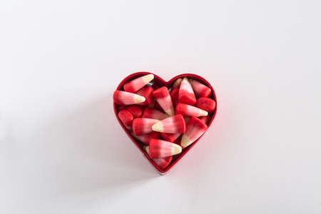 Valentines Day candy corn sweets in red cookie cutter on white backgroundの写真素材