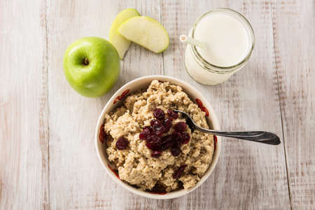 Heart healthy oatmeal breakfast cereal with apples and cranberries and glass of milkの写真素材