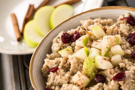 Close up of breakfast oatmeal with apples and cranberries and cinnamon sticksの写真素材