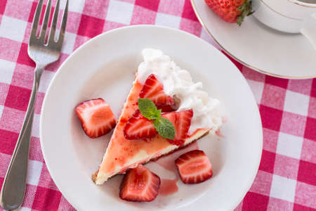 Fresh slice of cheesecake with strawberries and mint leaf from aboveの写真素材