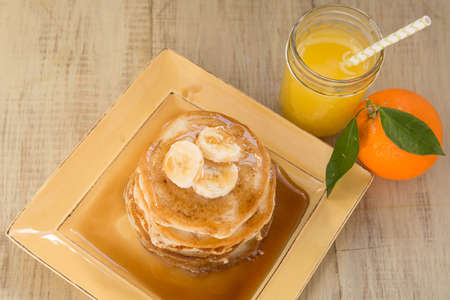 A stack of buttermilk pancakes and a glass of fresh squeezed orange juice for breakfast