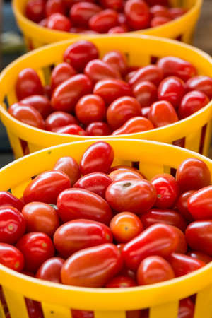 Tomatoes in yellow baskets for sale at farmers market in Asheville North Carolinaの写真素材