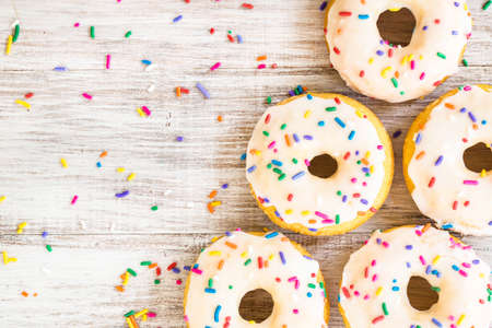Doughnuts on white wooden background for breakfast treat with colorful sprinklesの写真素材