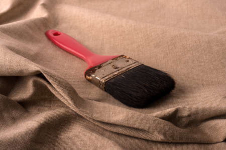 Old brush with red cape in against tissue background.の写真素材