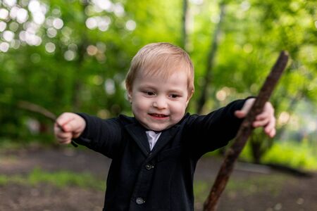 Cute caucasian kid play with a stick in the forestの写真素材