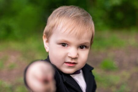 little boy 3-4 years old looks at the camera annoyingly and points a fingerの写真素材