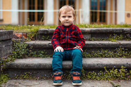 Portrait a boy sitting on outdoor concrete steps.の写真素材