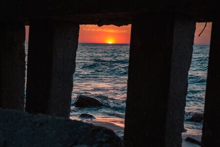 Sea shore and sunset through a concrete structureの写真素材