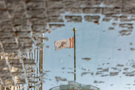 Moscow Region, Russia - September 22, 2019: Reflection in a puddle of the flag and the main gate of...