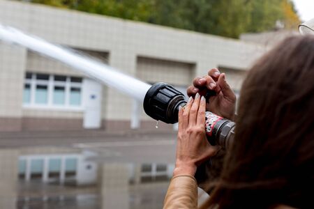 Hand with a fire nozzle. A stream of water spraying from a fire nozzle of a fire hose. Trainingの写真素材