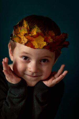 Portrait of a smiling 4-6 child with a crown of leaves on his head