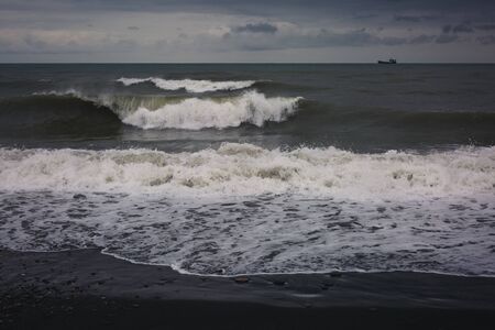 Splashing waves and cloudy sky on a pebble beach in Batumi. Nature concept, design for postcard or calendar. Autonomous Republic of Adjara, Georgia.の写真素材