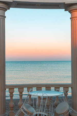 a white rotunda with tables and chairs. Sea view