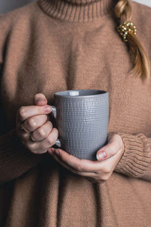 Cozy home. Female hands holding hot cup of tea.の写真素材