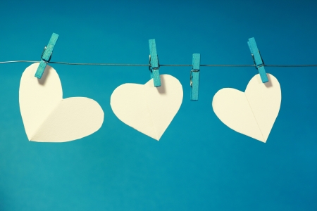 Three paper hearts pegged on a line with a blue background  One heart is missing の写真素材