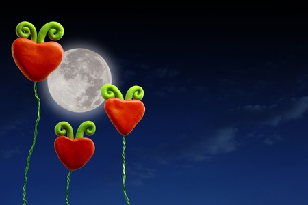 Three plasticine hearts under a moon lit sky の写真素材