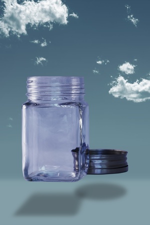 Empty bottle with lid off on a blue sky background の写真素材