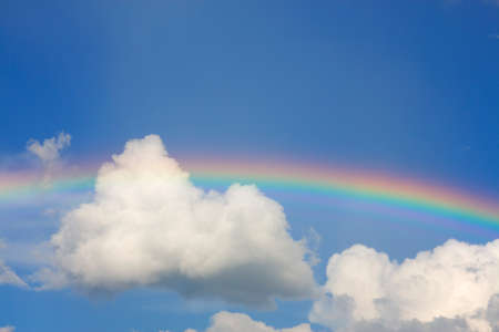 rainbow and white clouds on blue skyの写真素材
