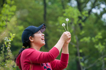 A smiling woman grabbing dandelionの写真素材