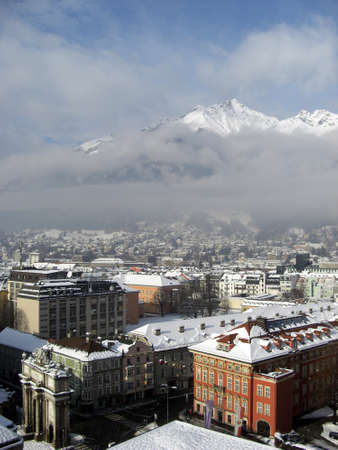 View on the city of Innsbruck during winter season with snow on the rooftops and the Alps in background the sky is a bit cloudyのeditorial素材