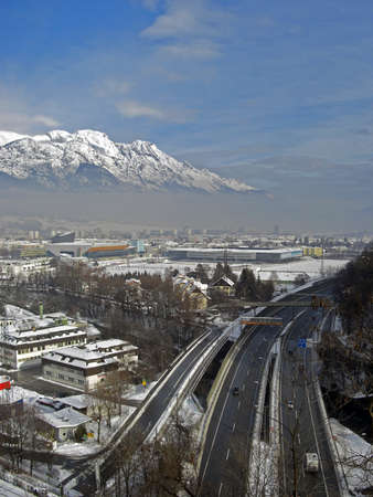 View on the city of Innsbruck during winter season with snow on the rooftops and the Alps in background the sky is a bit cloudyのeditorial素材