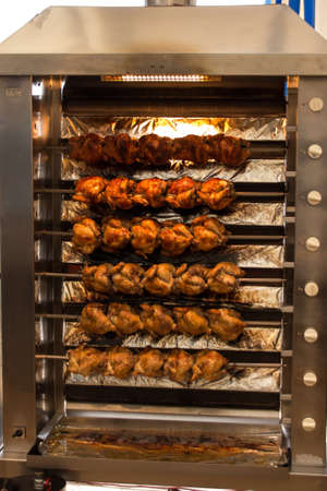 Broiling machine with lots of chicken turning to get brown and ready to serveの写真素材
