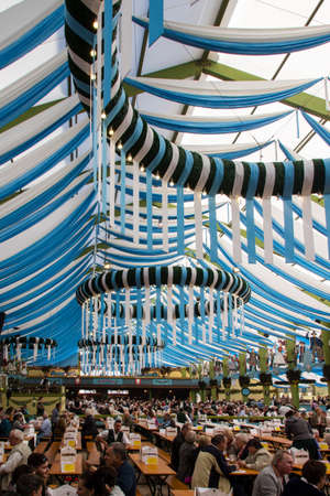 Inside the Ochsenbraterei beer tent at Oktoberfest with people celebrating and drinking beerのeditorial素材