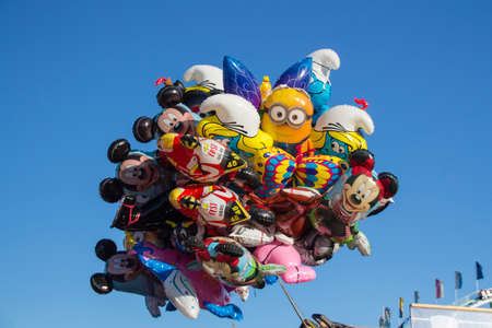 Famous sculptures as balloons (Mickey Mouse, Smurf)  flying above the fairground of Oktoberfestのeditorial素材
