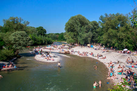 The Isar river in Munich with many unidentified people on a sunny day taking a sunbathのeditorial素材