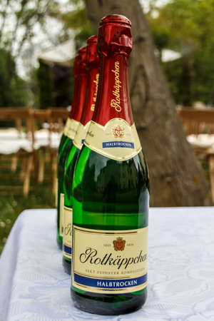 Four bottles with sparkling wine in a row (Rotkaeppchen brand) and chairs in the backgroundのeditorial素材