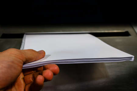 Dropping of paper in a metal bin container for safe disposal of business documentsの写真素材