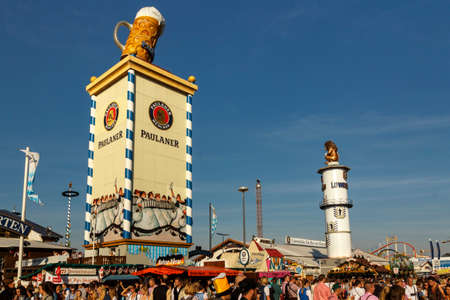 Munich, Germany - September 24, 2016: Roof of the Paulaner tower with the famous beer stein and the Loewnbraeu tower with the lion sculpture, unidentified people are walking byのeditorial素材