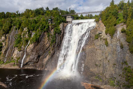 montmorency falls with rainbow and cloudy skyの写真素材
