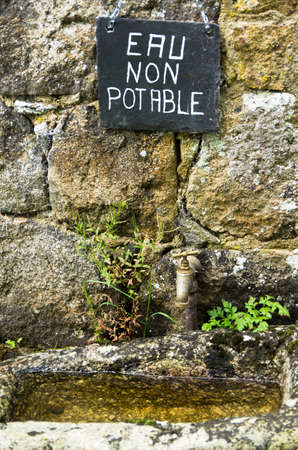 A French sign above an old basin and tapの写真素材
