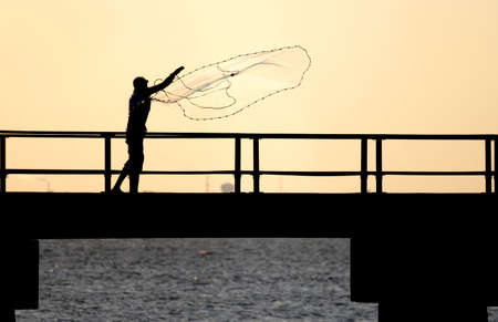 Fisherman tossing a net from a pier.の写真素材
