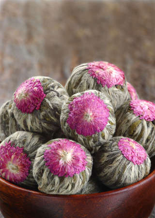 Several hand sewn balls of flowering tea in a bamboo bowl.の写真素材