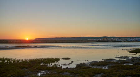 Tranquil landscape of the marsh at the mouth of the river under cloudless sundown sky in summer with Barbate town at background. Atlantic ocean coastline, Cadiz, Andalusia, Spainの写真素材