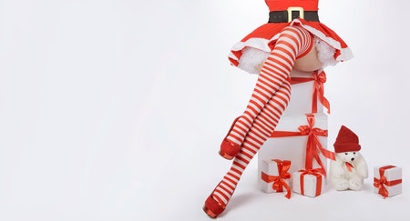 Sexy Santa Claus woman legs and christmas gifts. Beautiful sexy woman in Santa costume with long legs in striped stockings and red heels. white background with copy spaceの写真素材