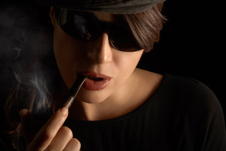 woman smoking pipe. Closeup studio portrait isolated on black background with copyspaceの写真素材