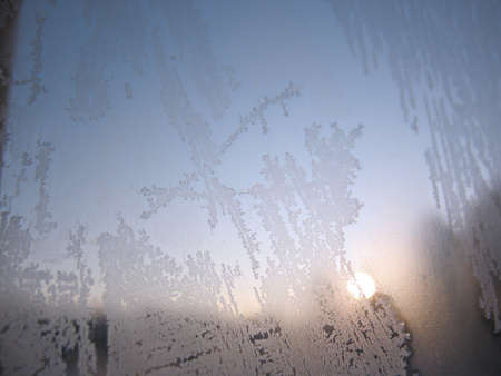 There are frosty pattern on glass winter window and sun