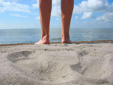 There are sand, legs, footprints, clouds, sly, skyline and  lakeの写真素材