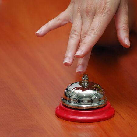 metallic hand-bell on a table, hand press button
