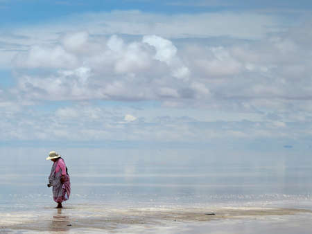 Salar de Uyuni, Bolivia - jan 26, 2014  - Bolivian woman on the perfect white flat salt desert with blue cloudy sky.のeditorial素材