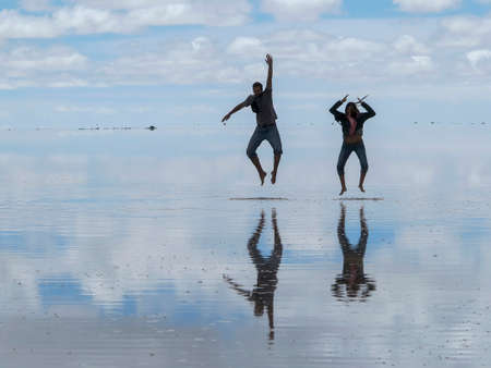 Salar de Uyuni, Bolivia - jan 26, 2014  - panorama of the perfect white flat salt desert with blue cloudy sky. Group of young people having fun posing and taking photosのeditorial素材