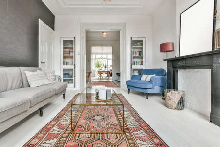 Living room with red carpet, mild sofa, glass table, and other furnitureの写真素材