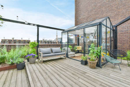 A large open-air terrace on the roof-top with lounge space and a small greenhouse with plantsの写真素材