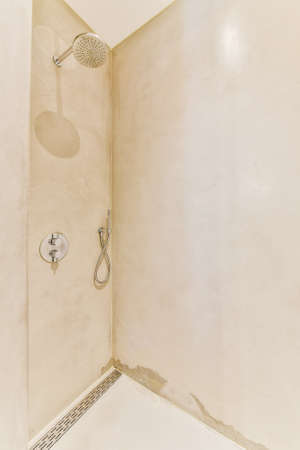 Shower tap and levers installed on shabby beige wall in modern bathroom at homeの写真素材
